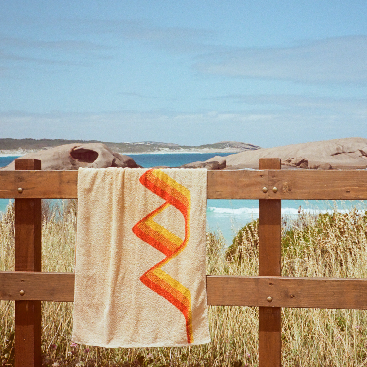 The Classics Beach Towel hanging over wooden railing. Twilight Beach, Esperance is in the background.
