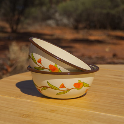 Two cream and brown coloured enamel bowls stacked on a wooden table in the outback. The bowls feature an Australian Natives inspired floral design around the outside