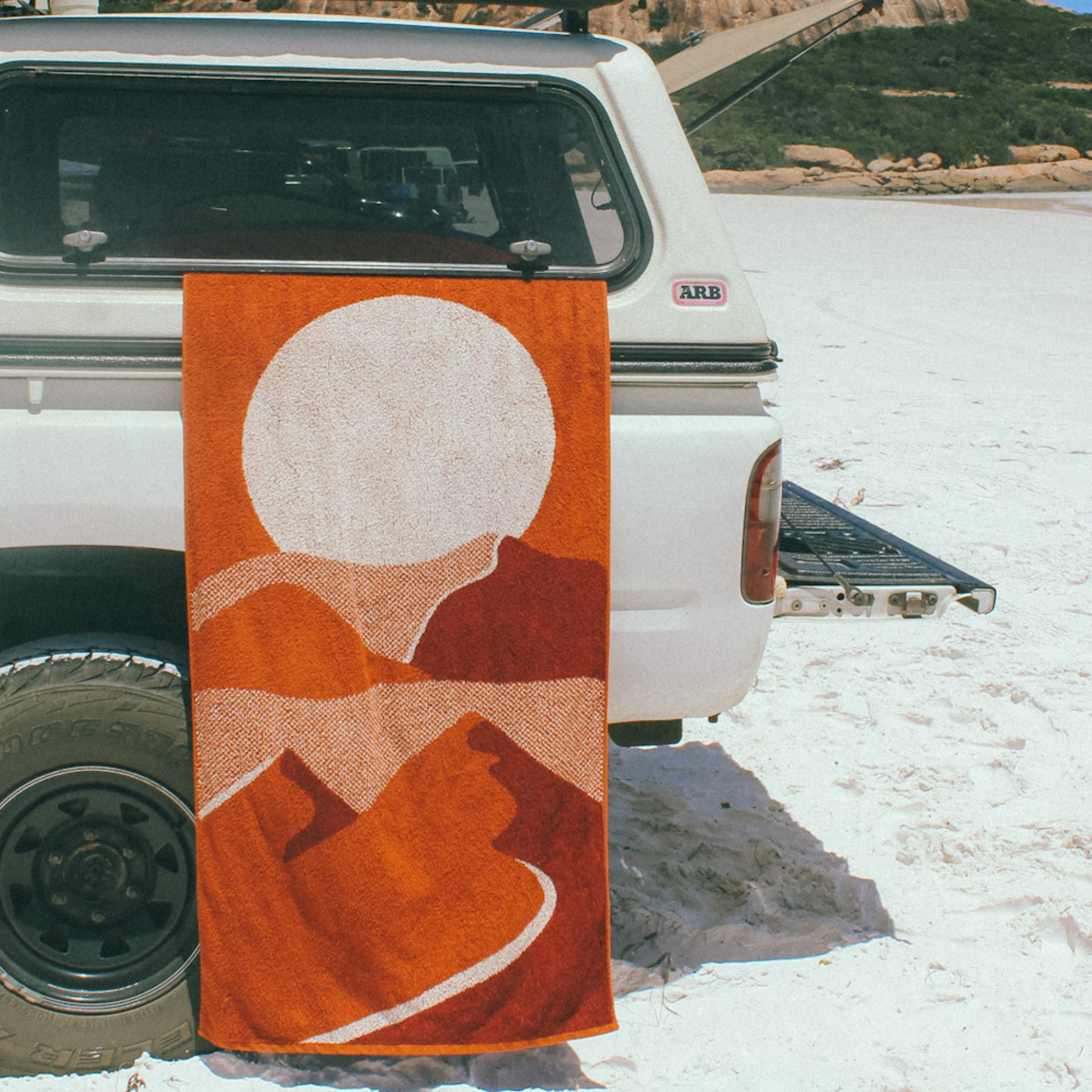 The Dunes Beach towel hanging out the side of a utes canopy on a beach in Australia