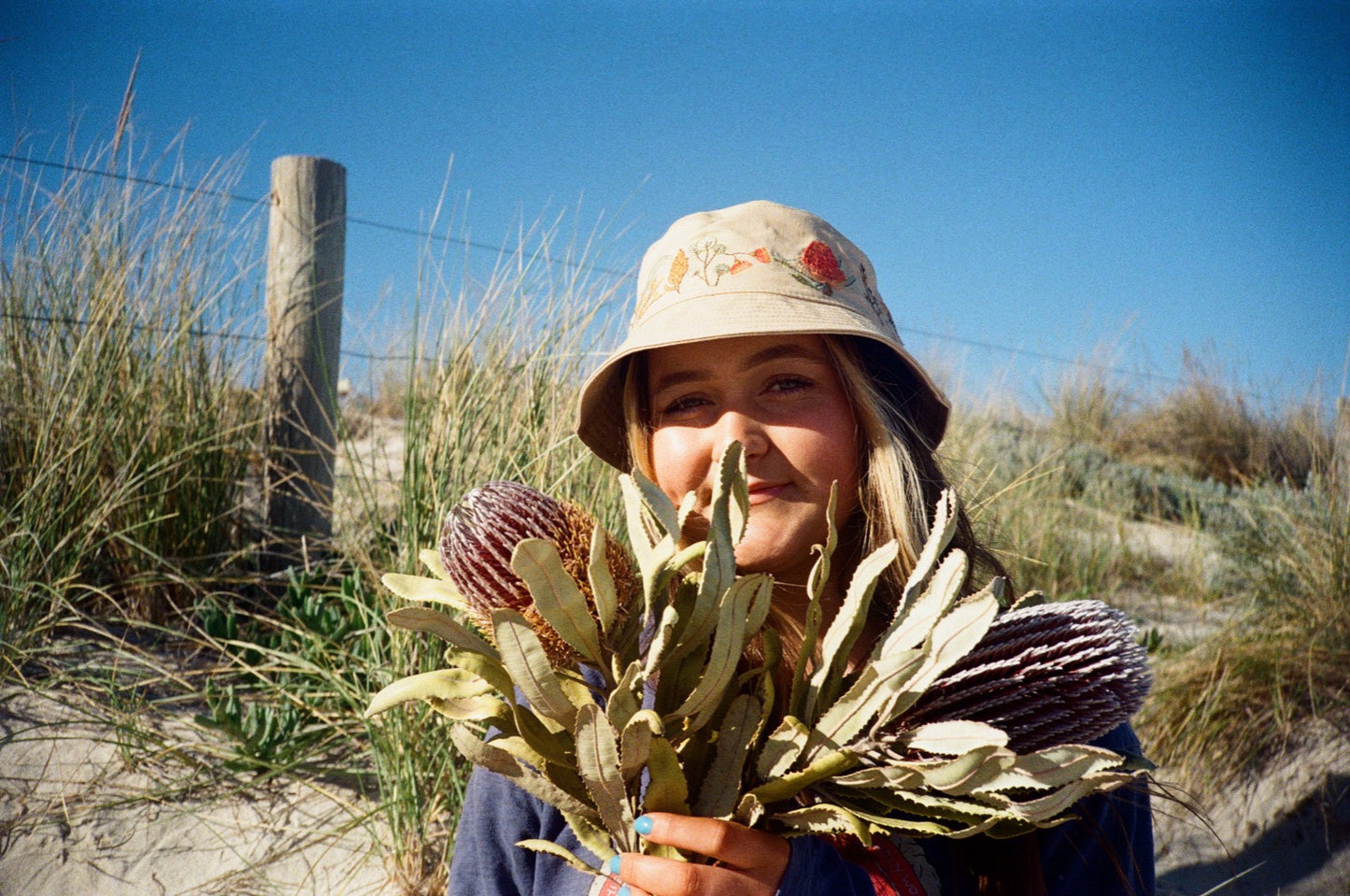 Australian natives Banksia hemp hat on brunette girl holding banksias at the beach