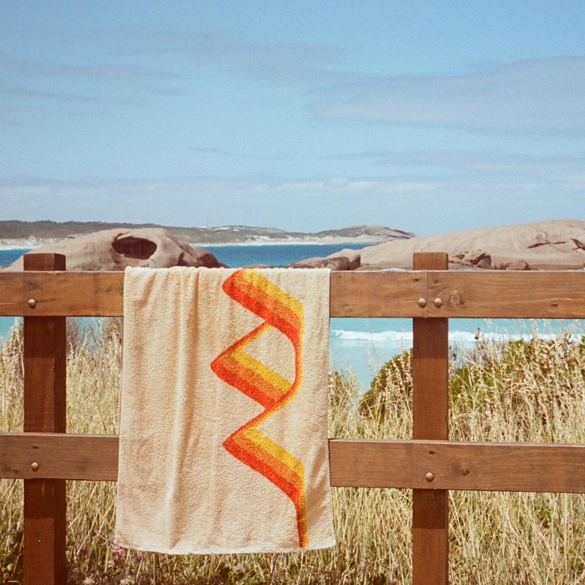 The Classics Beach Towel hanging over wooden railing. Twilight Beach, Esperance is in the background. 