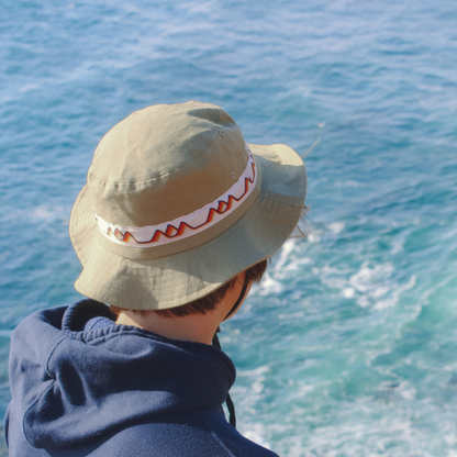 Man wearing a Salty Dunes Wide Brim looking down at the waves in the ocean from atop a cliff. 